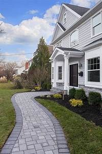 a brick walkway in front of a white house