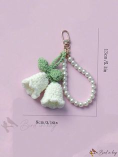 a key chain with two crocheted bells and a pearl bead necklace attached to it