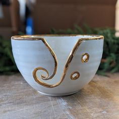 a white and gold bowl sitting on top of a wooden table