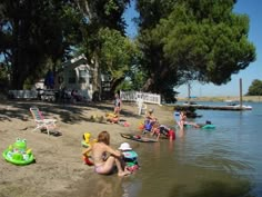 people are sitting on the beach by the water and inflatable toys near them