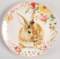 a plate with a painting of a rabbit on it's face and flowers around the edges