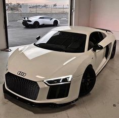 two white sports cars parked in a garage