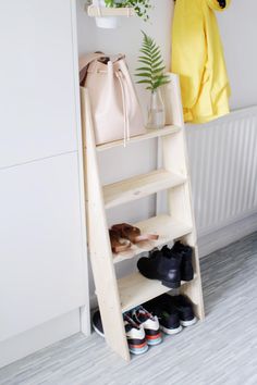 a wooden shelf with shoes on it next to a radiator and coat rack