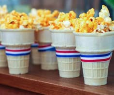 small cups filled with popcorn sitting on top of a wooden table next to each other