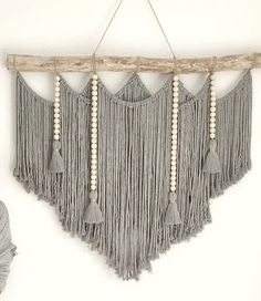 a wall hanging with tassels and beads on the ends, made from driftwood