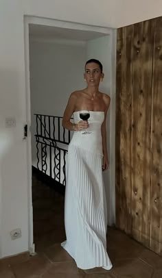 a woman in a white dress holding a glass of wine