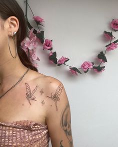 a woman with tattoos on her chest and behind her ear is a pink flower garland