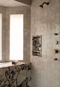 a bath room with a shower head and a marble counter top next to a window