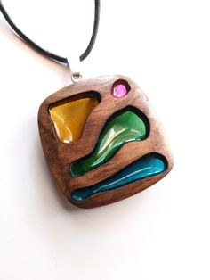 a wooden pendant with colorful glass pieces on it's back end and a black cord