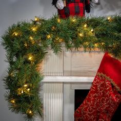 a teddy bear sitting on top of a mantel decorated with christmas stockings and lights