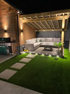 an outdoor living area is lit up with lights and green grass on the ground,