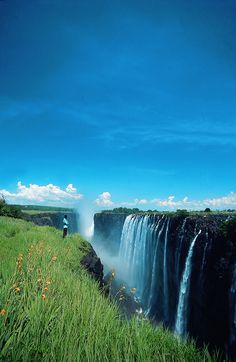 a man standing at the edge of a waterfall with water pouring from it's side