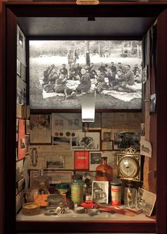 a room with many pictures on the wall and various items in front of it, including an old clock