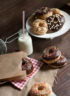 several donuts are on plates with sprinkles next to a glass of milk