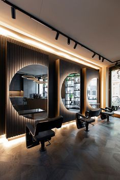 the interior of a modern salon with mirrors and black benches in front of large windows