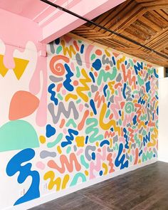 a large colorful painting on the side of a wall next to a wooden ceiling with exposed rafters