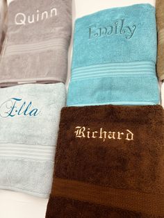 four personalized towels are lined up on a table with the name embroidered on them