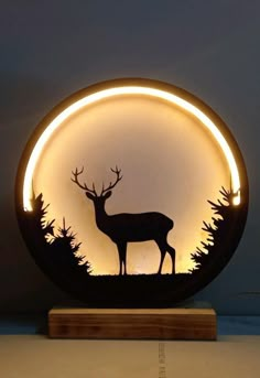 a deer is silhouetted in the center of a circular light with trees around it