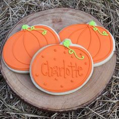 three decorated cookies sitting on top of a wooden slice in the grass next to some dry grass