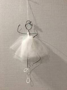 an ornament hanging from a string on a white wall with strings attached to it