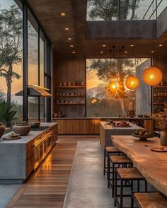 an open kitchen and dining room area with wooden floors, large windows, and modern lighting fixtures