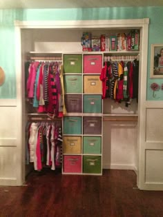 a closet filled with lots of clothes and boxes next to a wall mounted shelf that has pictures on it