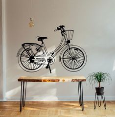 a bicycle wall decal on a white wall next to a wooden table and potted plant