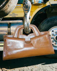 a brown purse sitting next to a yellow truck