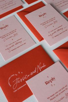 red and pink wedding stationery with white writing on it's envelopes are arranged in rows