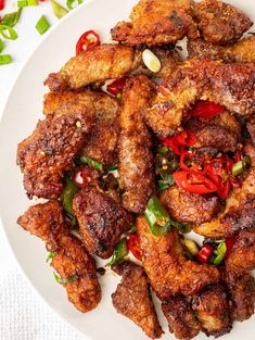 chicken wings with peppers and onions on a white plate