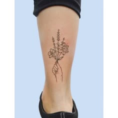 a woman's foot with a flower tattoo on her left leg and one hand holding flowers