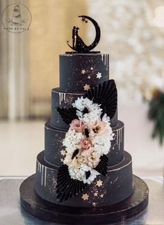 a three tiered wedding cake with flowers and stars on the top is decorated with black icing