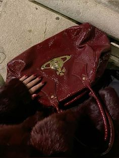 a woman's hand holding onto a red purse