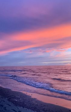 the sun is setting at the beach with waves coming in