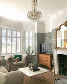 a living room filled with furniture and a chandelier hanging from the ceiling over a fire place