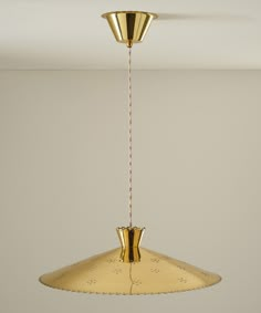 a gold colored pendant light hanging from a ceiling in a room with white walls and flooring