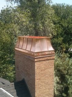 a brick chimney on top of a roof with trees in the background