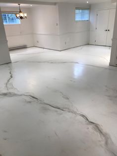 an empty room with white walls and marble flooring in the foreground is a doorway leading to another room