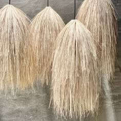 three straw umbrellas hanging from the side of a building