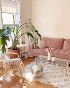 a living room with pink couches and white rugs on the wooden flooring