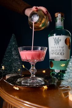 a bottle of alcohol being poured into a small glass with a pink substance in it