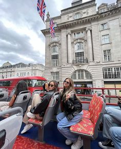 two women sitting on seats in front of a building with an union jack flag hanging from the roof