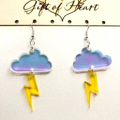 pair of earrings with lightning bolt and cloud on white card board, against sign that says artful heart