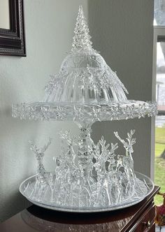 a clear glass cake stand sitting on top of a wooden table