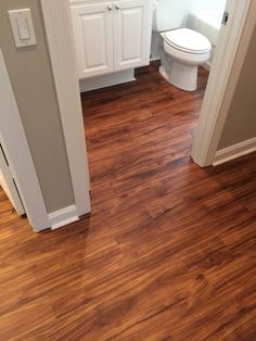 a bathroom with wood floors and white cabinets