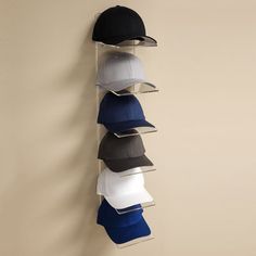 six hats hanging on the wall in front of a hat rack with five different colors