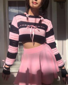 a woman wearing a pink skirt and black crop top with her hands on her hips