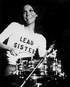 a woman is playing the drums while wearing a t - shirt that says lead sister