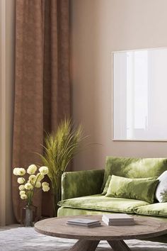 a living room with green velvet couches and white flowers in vases on the coffee table