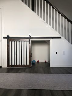 an empty room with a dog crate in the middle and stairs leading up to it